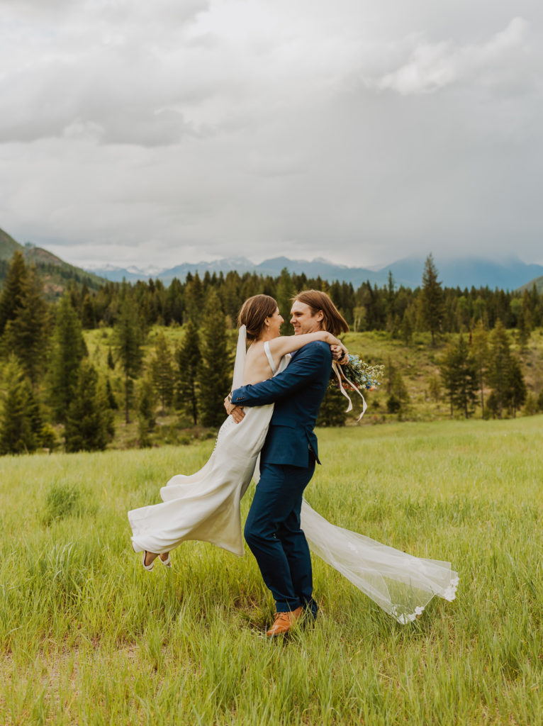 Bride and groom spinning in a field after Glacier National Park Lake McDonald elopement.