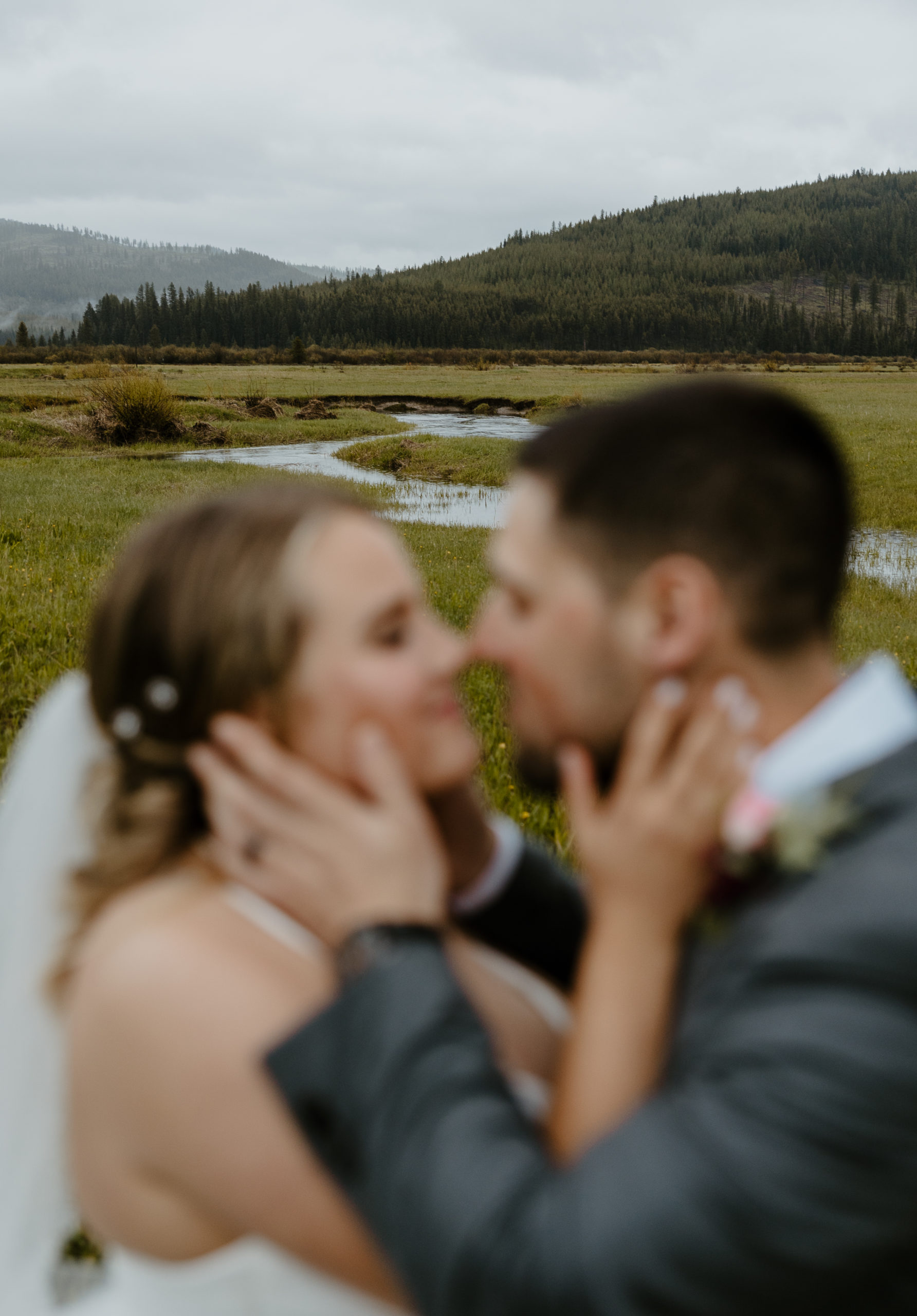 Husband and wife embracing in front of mountains and meadow view