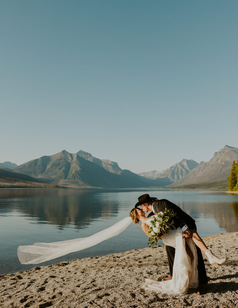 Bride and groom dip kiss in front of Lake McDonald. Glacier National Park Photography by Haley Jessat
