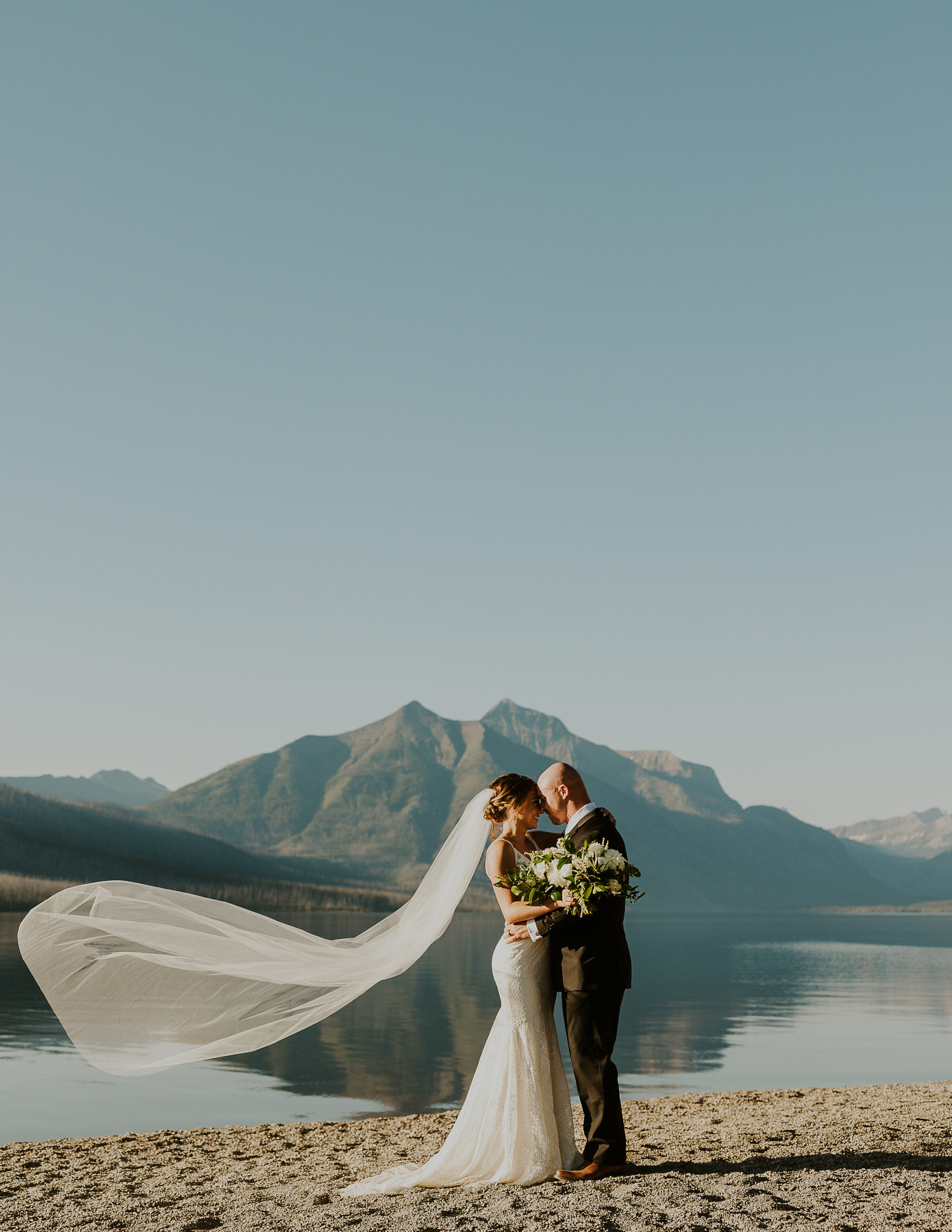 Elopement photography by Haley J Photo. Bride and groom in front of Lake McDonald in Glacier National Park 