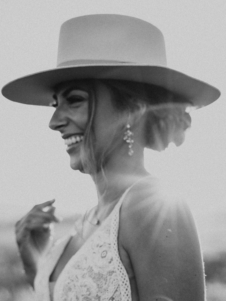 Black and white photo of the Bride smiling with a hat on. Glacier National Park Photography by Haley Jessat