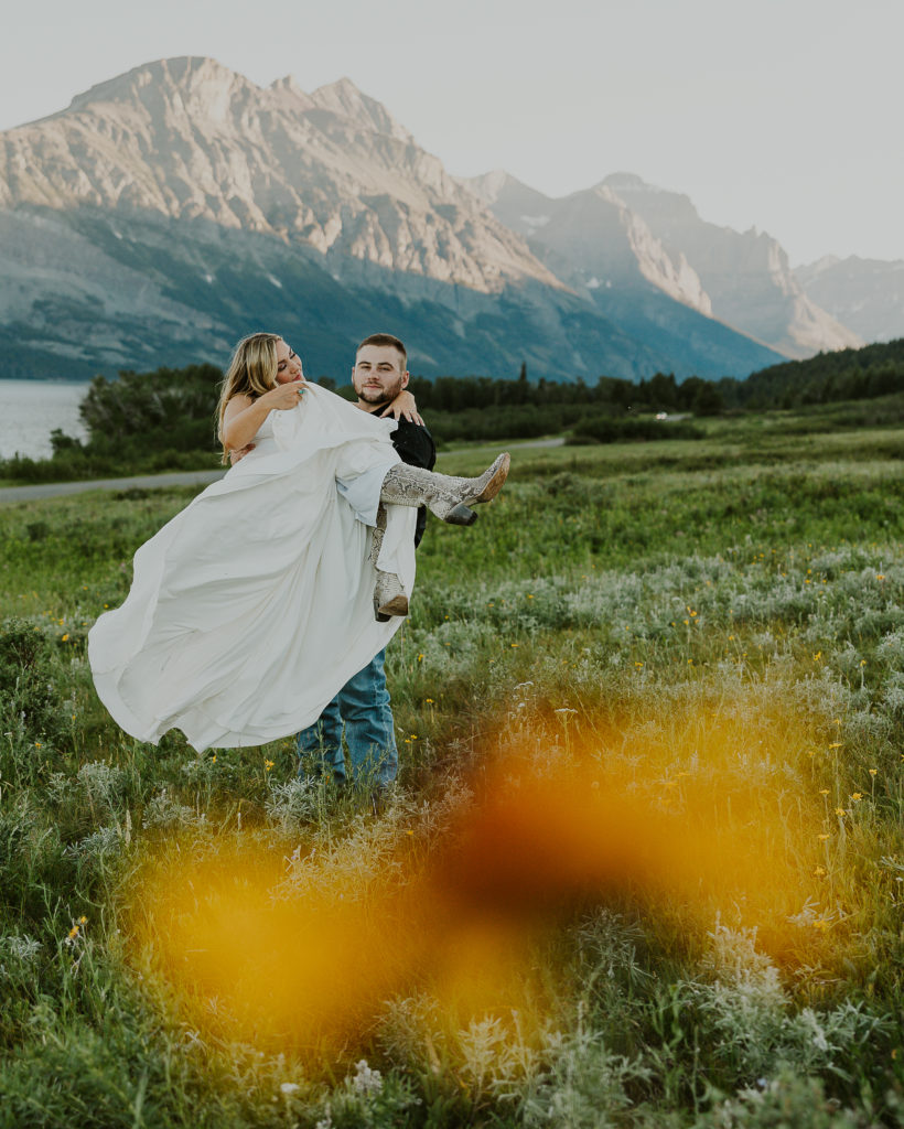 Groom carrying bride through Glacier National Park