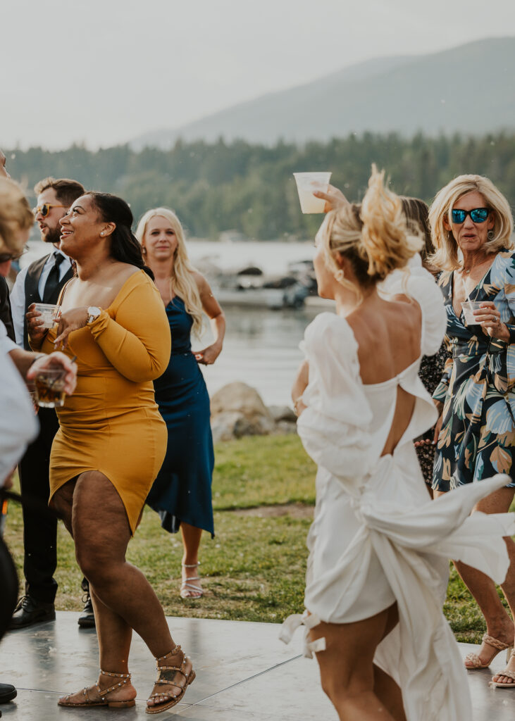Bride dancing at wedding reception near a lake with mountains