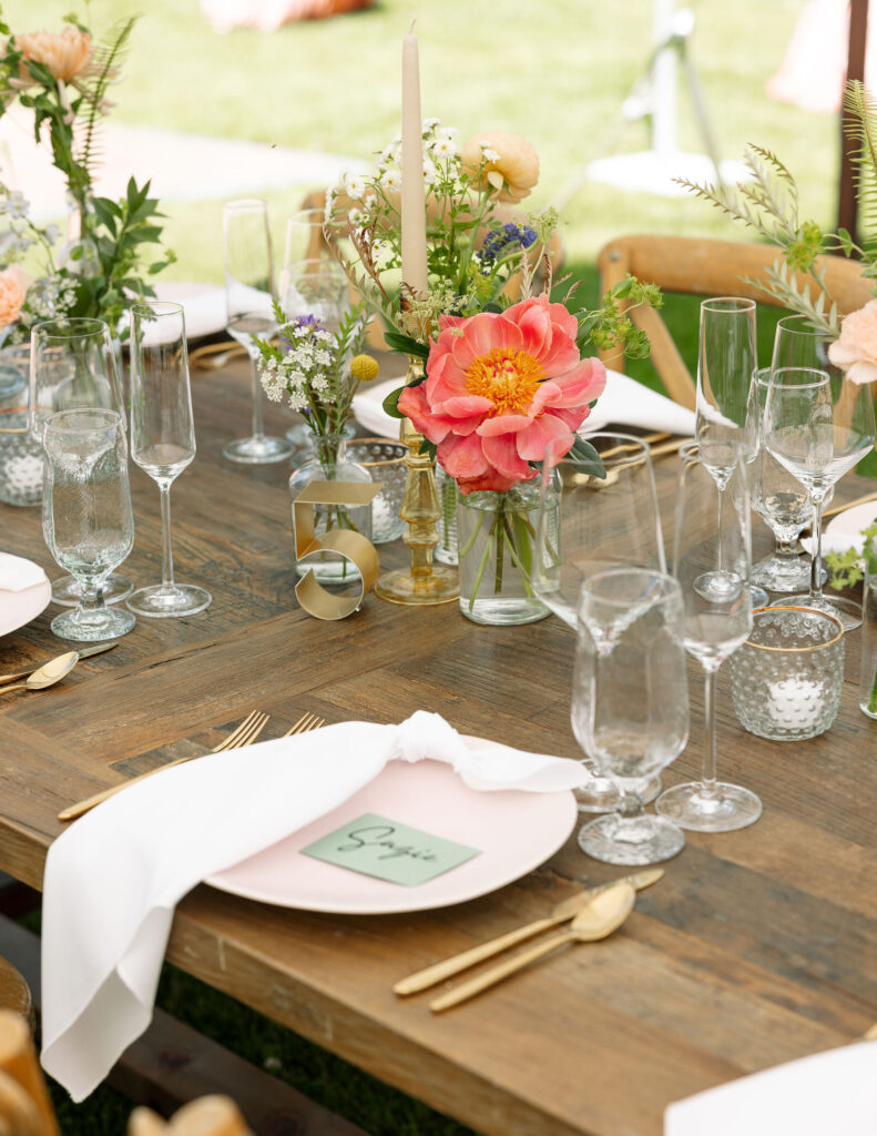 Close-up of a beautifully set wedding table with floral centerpieces, glassware, and rustic decor, highlighting the elegant setup at Amen Ranch.