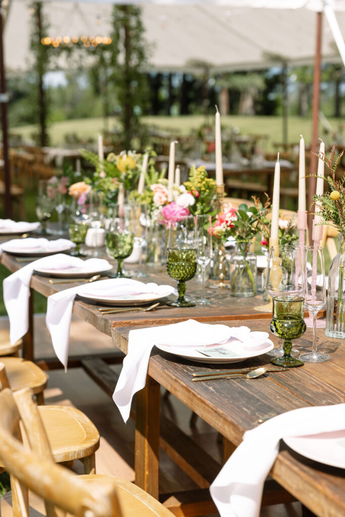 Long tables decorated with floral arrangements and candles under a canopy, showcasing the rustic charm of an outdoor Montana wedding at Amen Ranch.