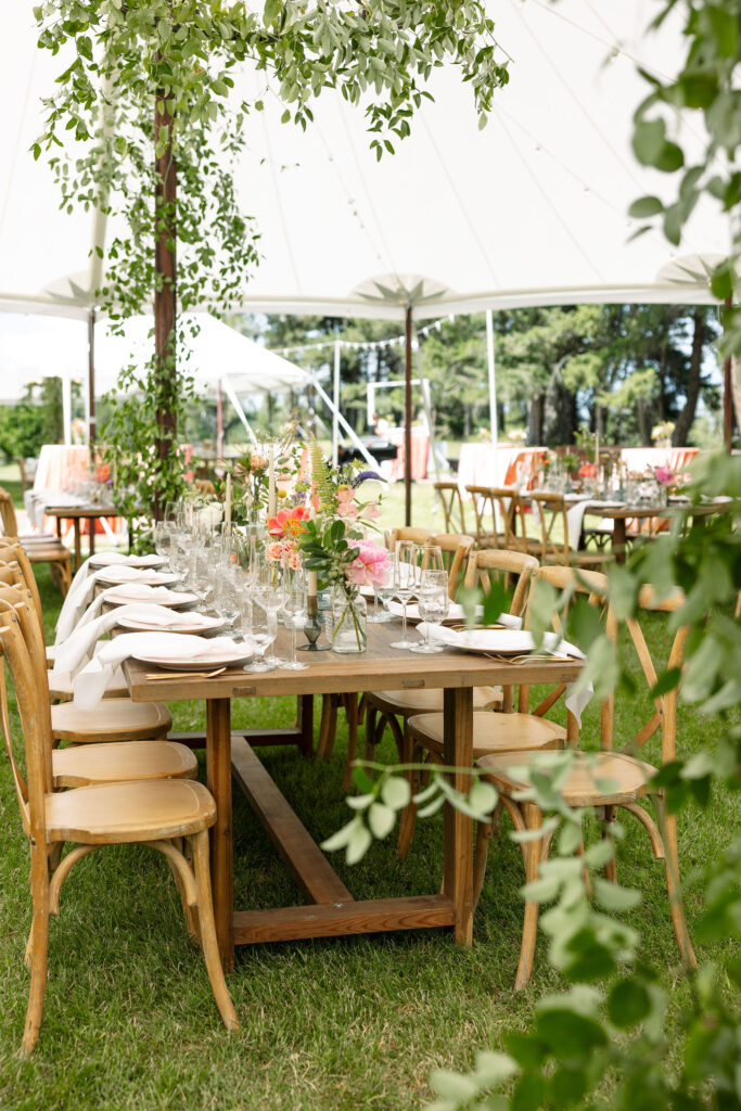 Elegant outdoor reception area at Amen Ranch with rustic wooden tables and chairs under a white canopy, beautifully decorated for a Montana ranch wedding.