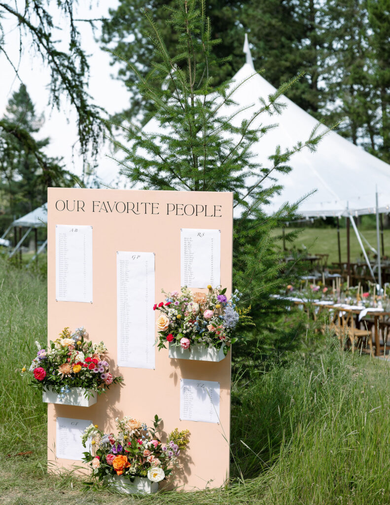 Wedding seating chart display labeled "Our Favorite People," decorated with fresh flowers and set against a natural backdrop at Amen Ranch in Montana.

