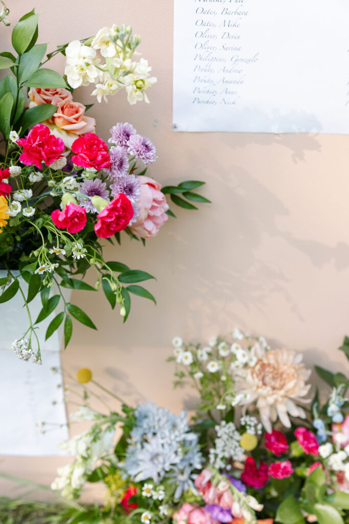 Detail shot of a wedding seating chart adorned with vibrant flowers, featuring handwritten guest names, adding a personalized touch to the decor at Amen Ranch in Montana.