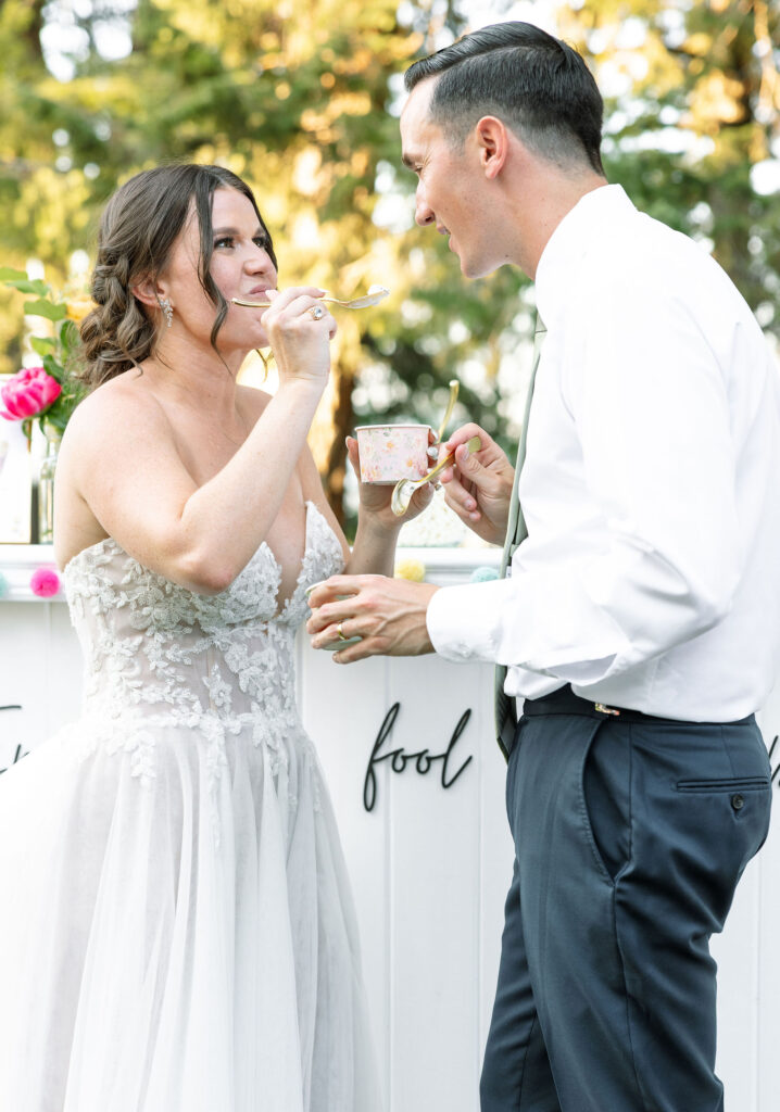 Bride and groom sharing a lighthearted moment and enjoying a dessert together during their wedding reception, showcasing their joy and celebration at a Montana ranch wedding.