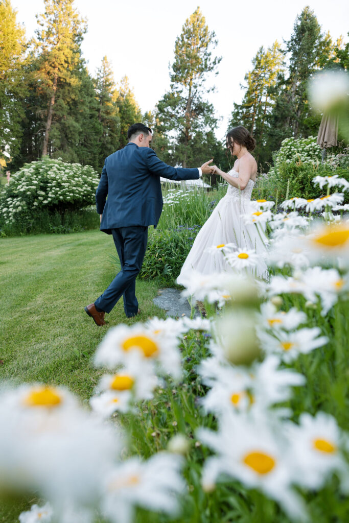 Bride and groom dancing in a garden surrounded by white flowers, creating a romantic and whimsical scene at a Montana ranch wedding.