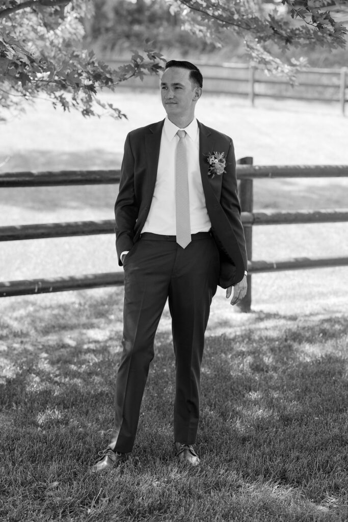 Black and white photo of the groom standing under a tree, looking contemplative before the ceremony at Amen Ranch in Montana.