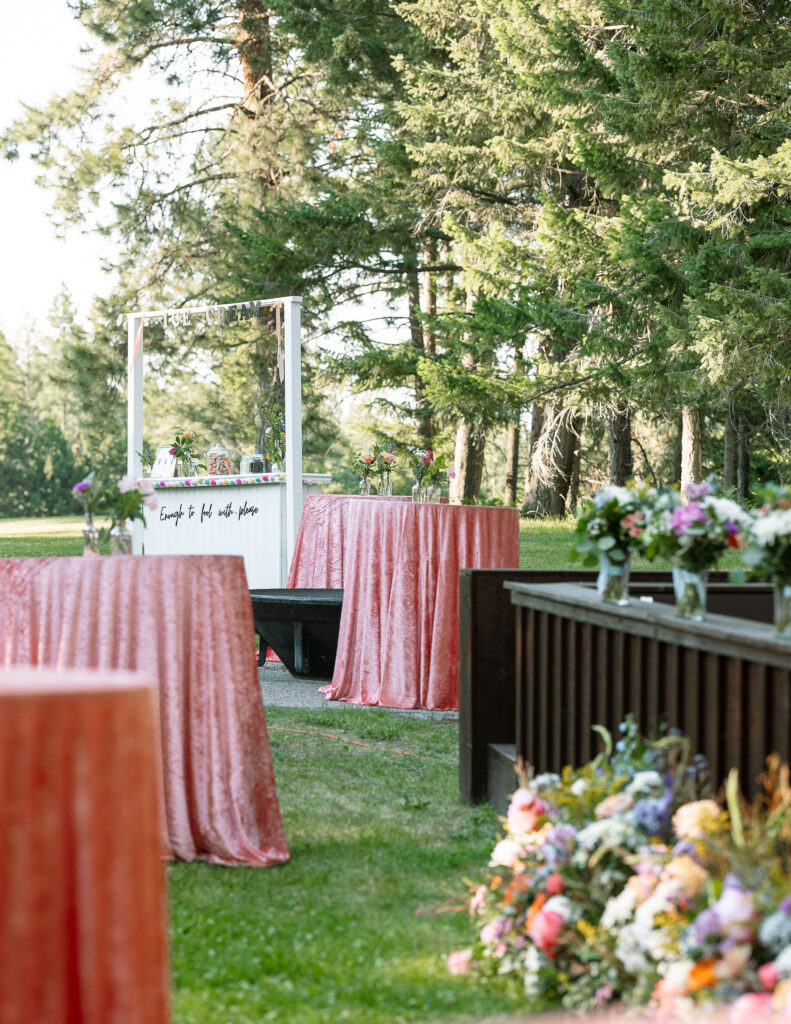 Outdoor reception area at Amen Ranch with a decorative table setup, featuring pink tablecloths and floral arrangements, creating a festive atmosphere for a Montana wedding.