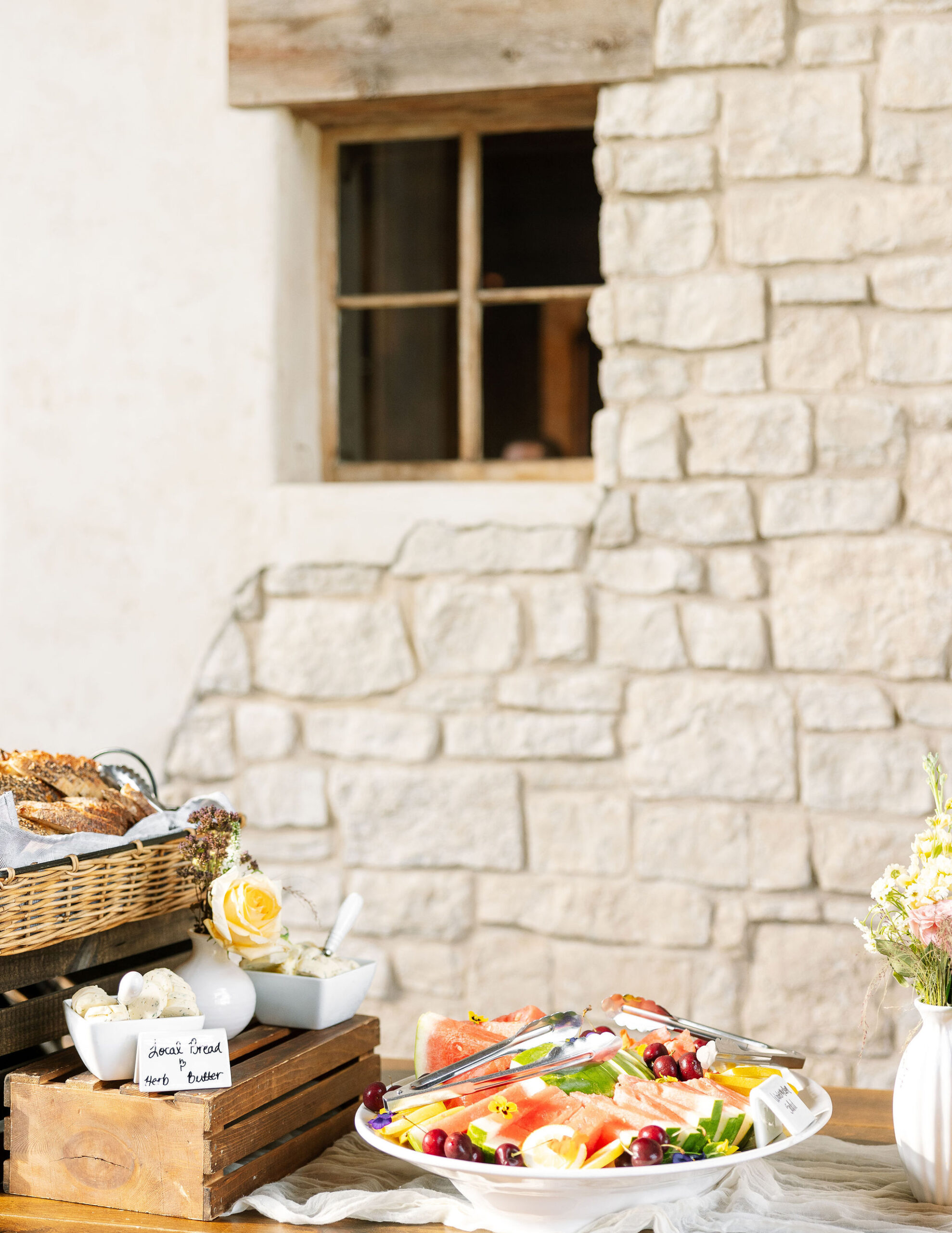 A vibrant salad display set against a stone wall at Copper Rose Ranch Wedding Venue. Captured by Haley J Photo, a Montana Wedding Venue Photographer.