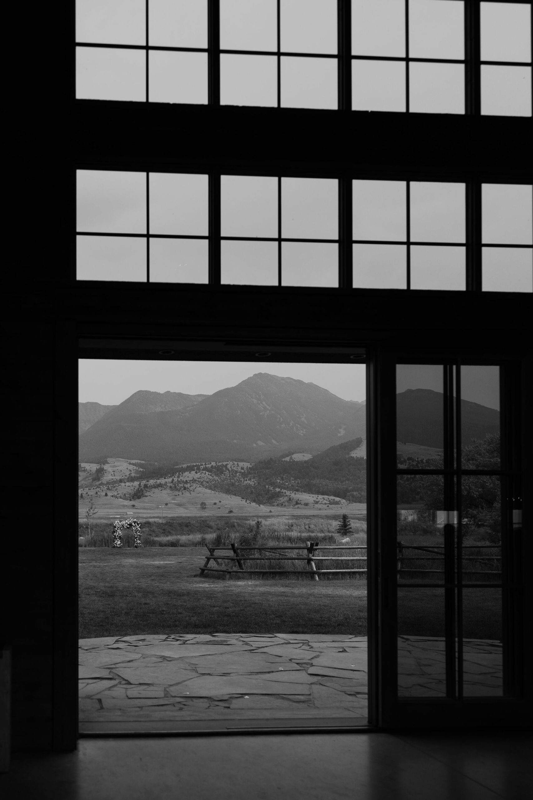 Black and white view through barn doors at Copper Rose Ranch Wedding Venue, showcasing the Montana mountains beyond. Captured by Montana Wedding Photographer Haley J Photo.