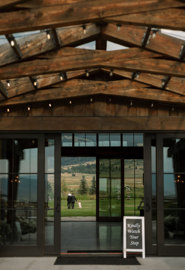 A view through the open barn doors at Copper Rose Ranch Wedding Venue, with a sign welcoming guests to the wedding. Captured by Haley J Photo, a Montana Wedding Venue Photographer.