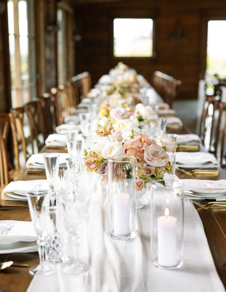 A beautifully set dining table with soft pink and white floral arrangements at Copper Rose Ranch Wedding Venue. Captured by Montana Wedding Photographer Haley J Photo.