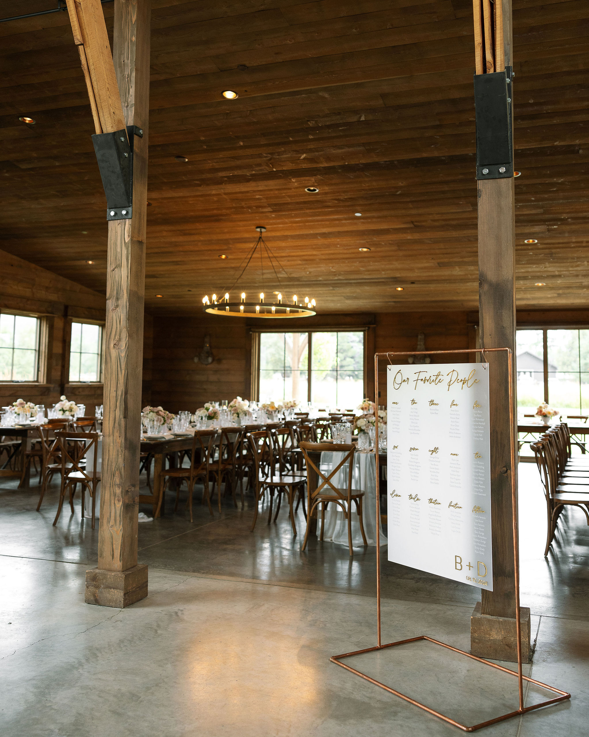 An indoor view of the rustic yet elegant reception area at Copper Rose Ranch Wedding Venue in Montana. The seating chart and wooden tables with floral arrangements create a welcoming atmosphere, captured by Haley J Photo, a Montana Wedding Photographer.