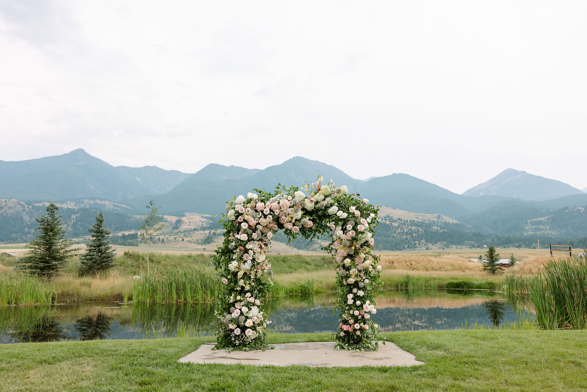 A floral arch set up for an outdoor ceremony at Copper Rose Ranch Wedding Venue, with the stunning Montana mountains in the background. The lush, natural setting is beautifully photographed by Haley J Photo, a Montana Wedding Venue Photographer.

