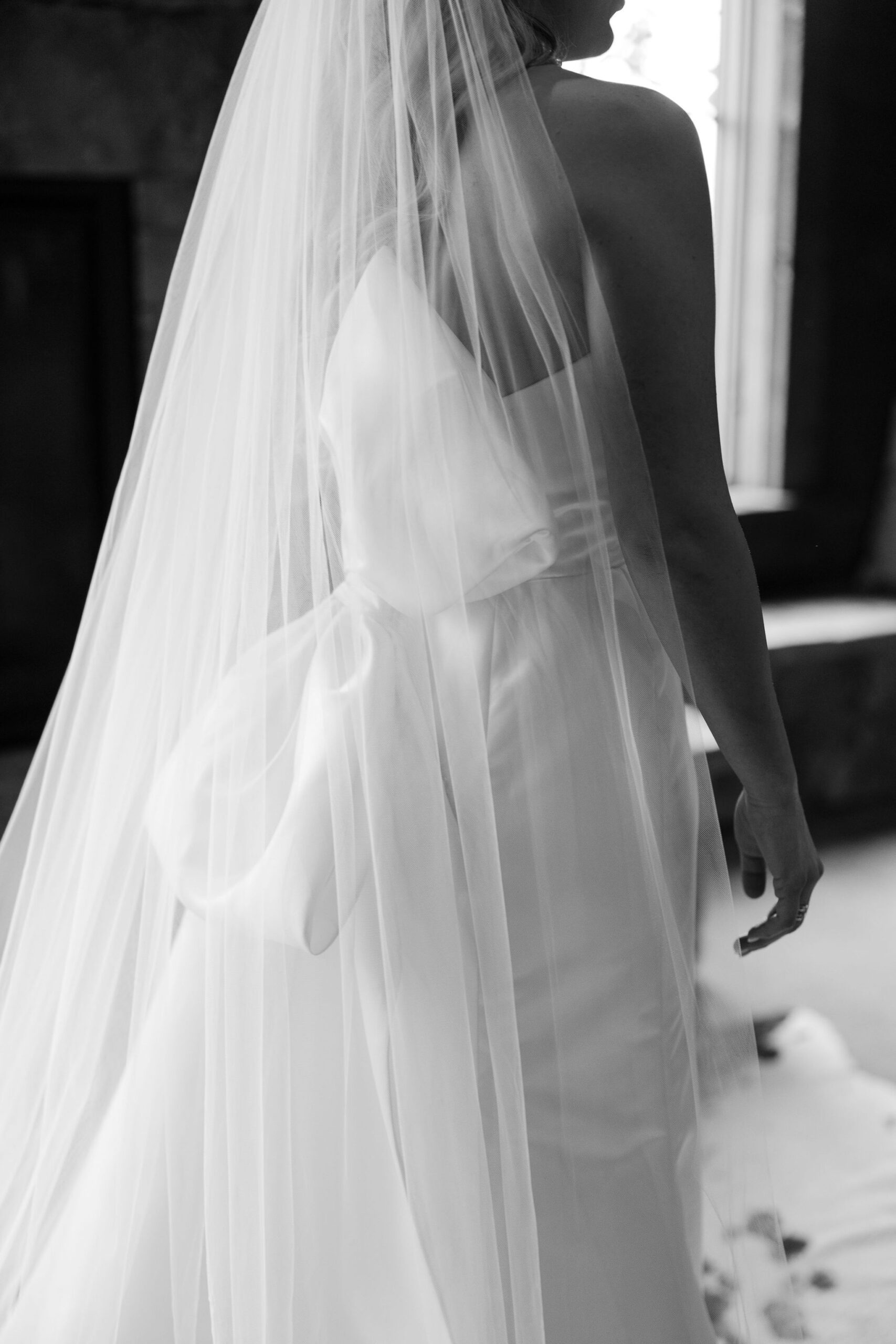 A close-up, black and white shot of the Montana Bride’s dress and veil as she walks towards the ceremony at Copper Rose Ranch Wedding Venue. The details of the gown and the elegance of the moment are highlighted by Haley J Photo, a Montana Wedding Photographer.