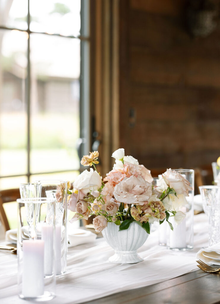  Close-up of a floral centerpiece with crystal glassware on a reception table at Copper Rose Ranch Wedding Venue. Captured by Montana Wedding Photographer Haley J Photo.