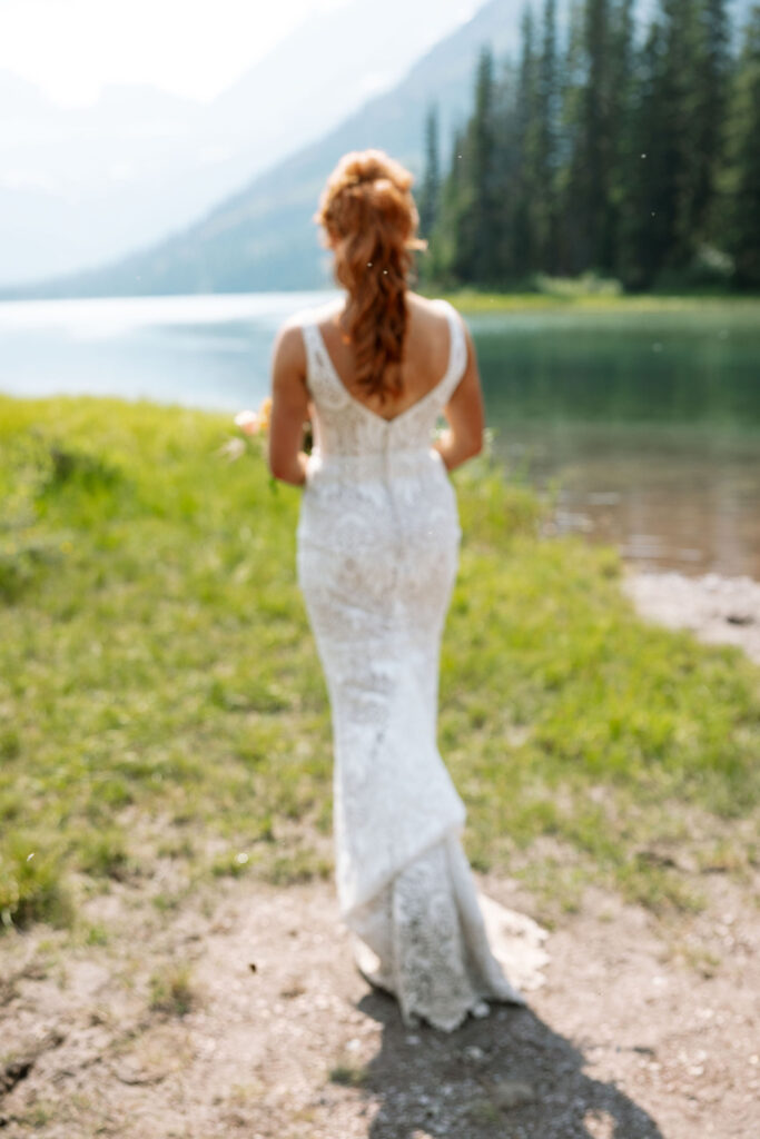 Bride walking along the lake's edge, surrounded by natural beauty during their Glacier National Park elopement.