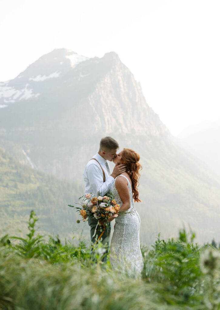 Bride and groom sharing a kiss with a beautiful mountain backdrop during their Glacier National Park elopement.