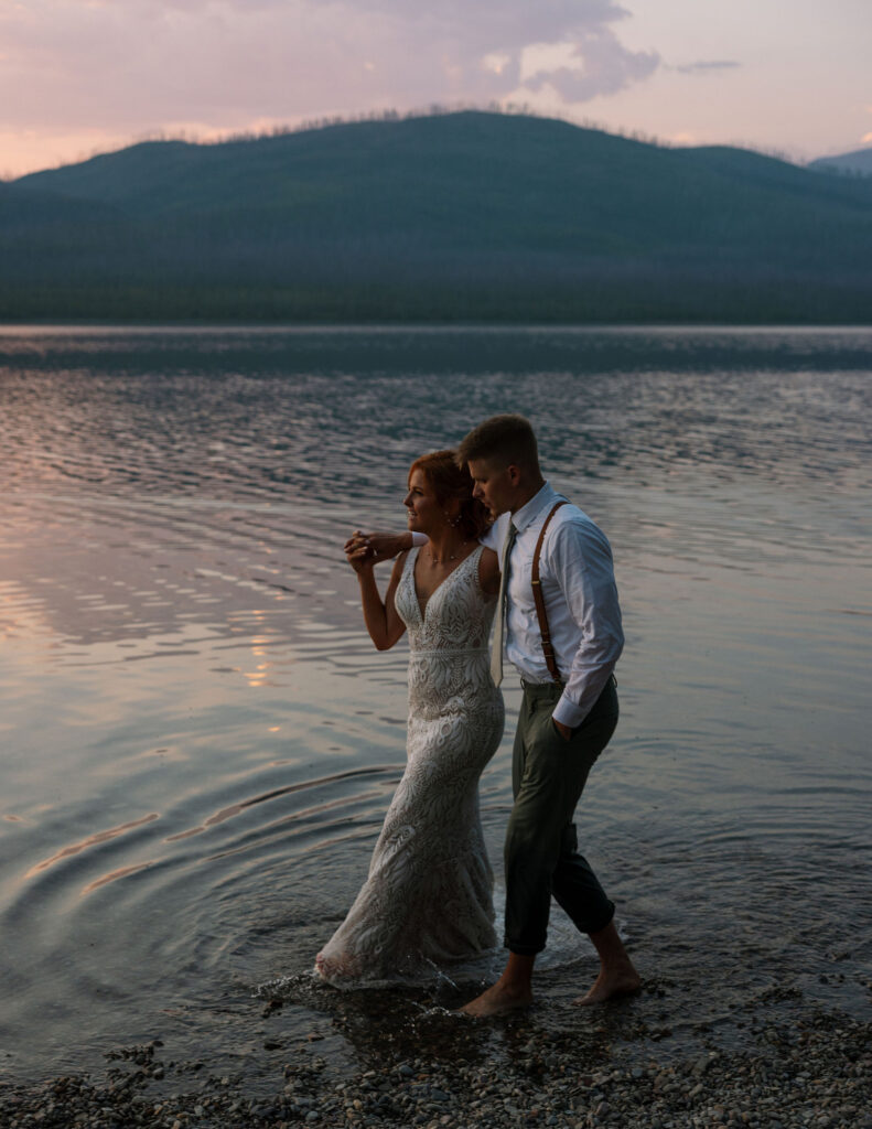 Bride and groom standing together in the water at sunset during their Glacier National Park elopement