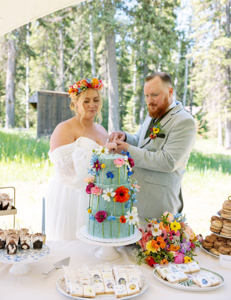 Bride and groom cutting their colorful wedding cake decorated with fresh flowers