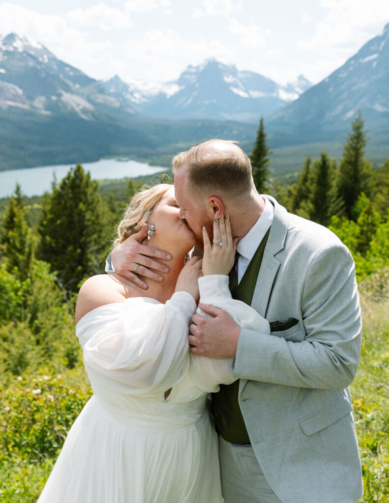 Bride and groom kissing in a scenic outdoor landscape, celebrating their elopement.