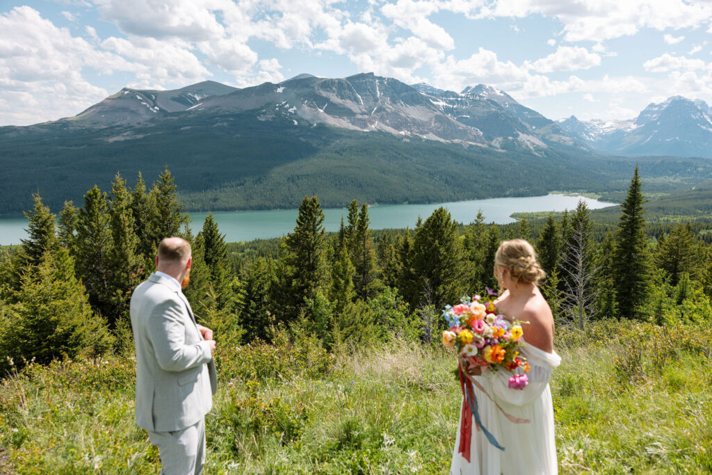 Bride and groom standing on a scenic overlook, gazing into each other's eyes with Montana's mountains in the background.
