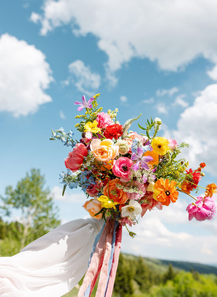 Close-up shot of a vibrant bouquet featuring colorful flowers, with the stunning Montana mountains in the background.