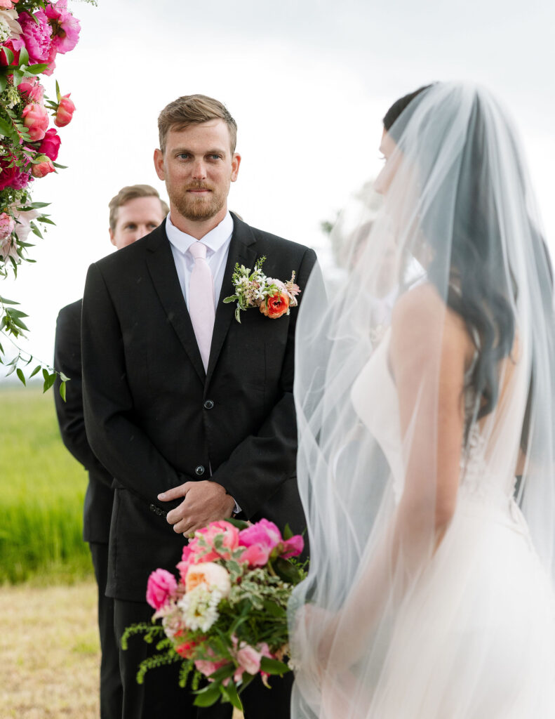 Groom smiling at the bride, both framed by vibrant flowers, a beautiful moment in Montana wedding photography.