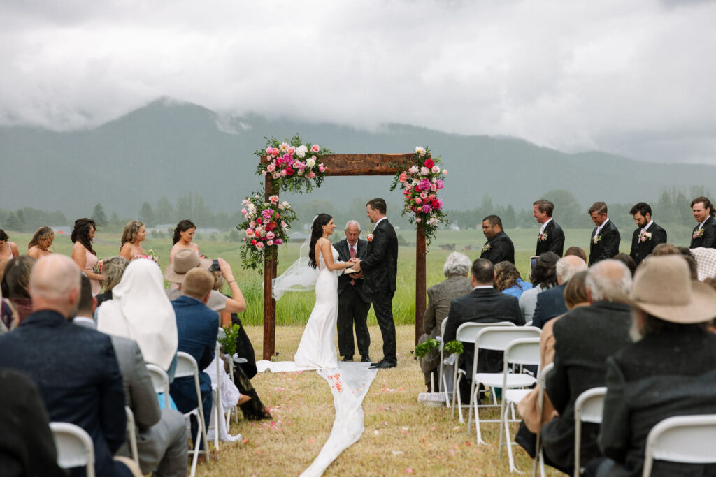 Outdoor ceremony with a floral arch and mountain backdrop, exemplifying storytelling wedding photography by Haley J Photo.