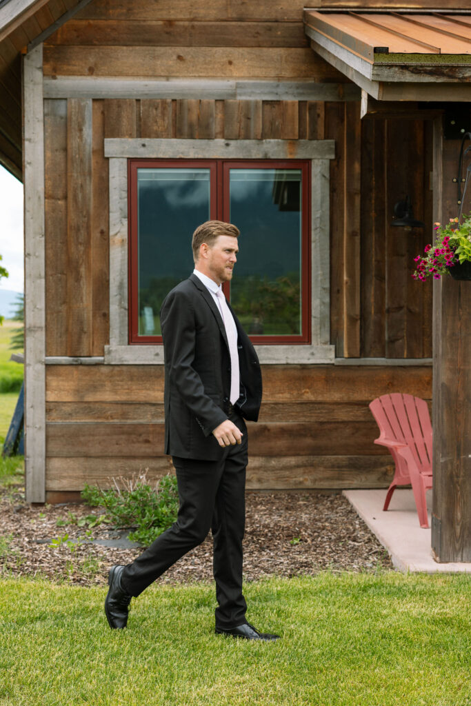 Groom walking by a rustic barn, showcasing Montana wedding storytelling photography.