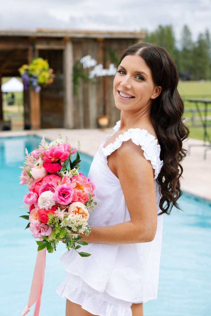 Bride playfully dipping her toes in the pool with her bouquet, a storytelling photography moment.