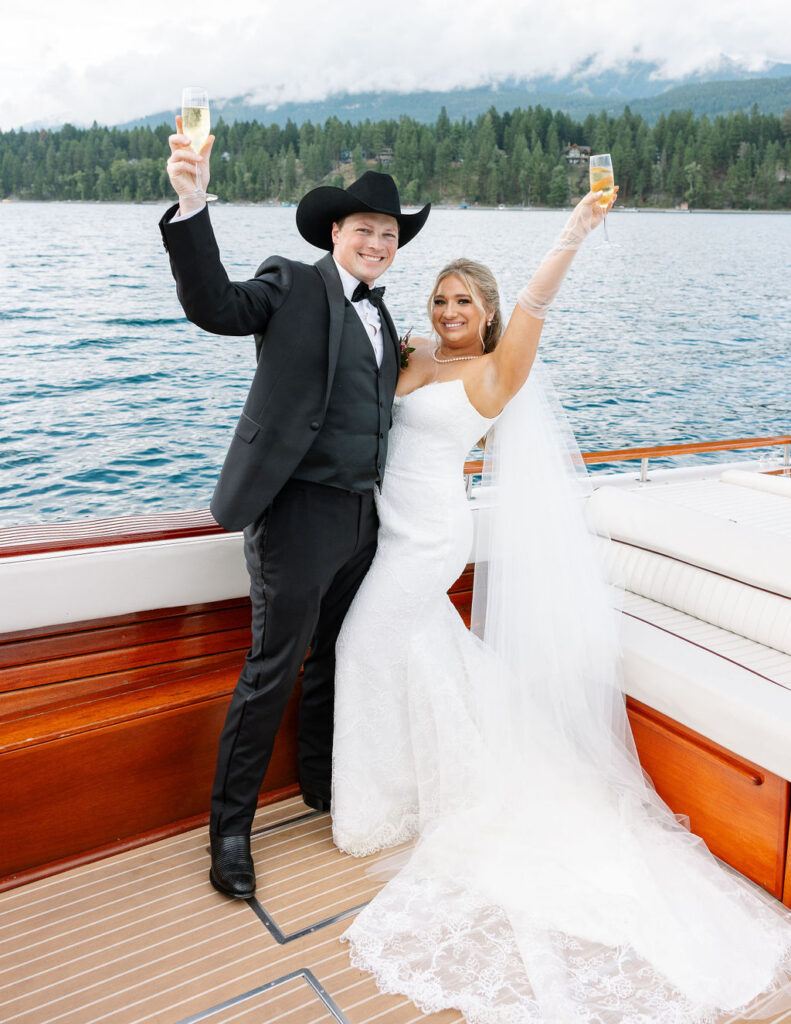 Bride and groom cheer on boat post-ceremony at Whitefish Montana wedding