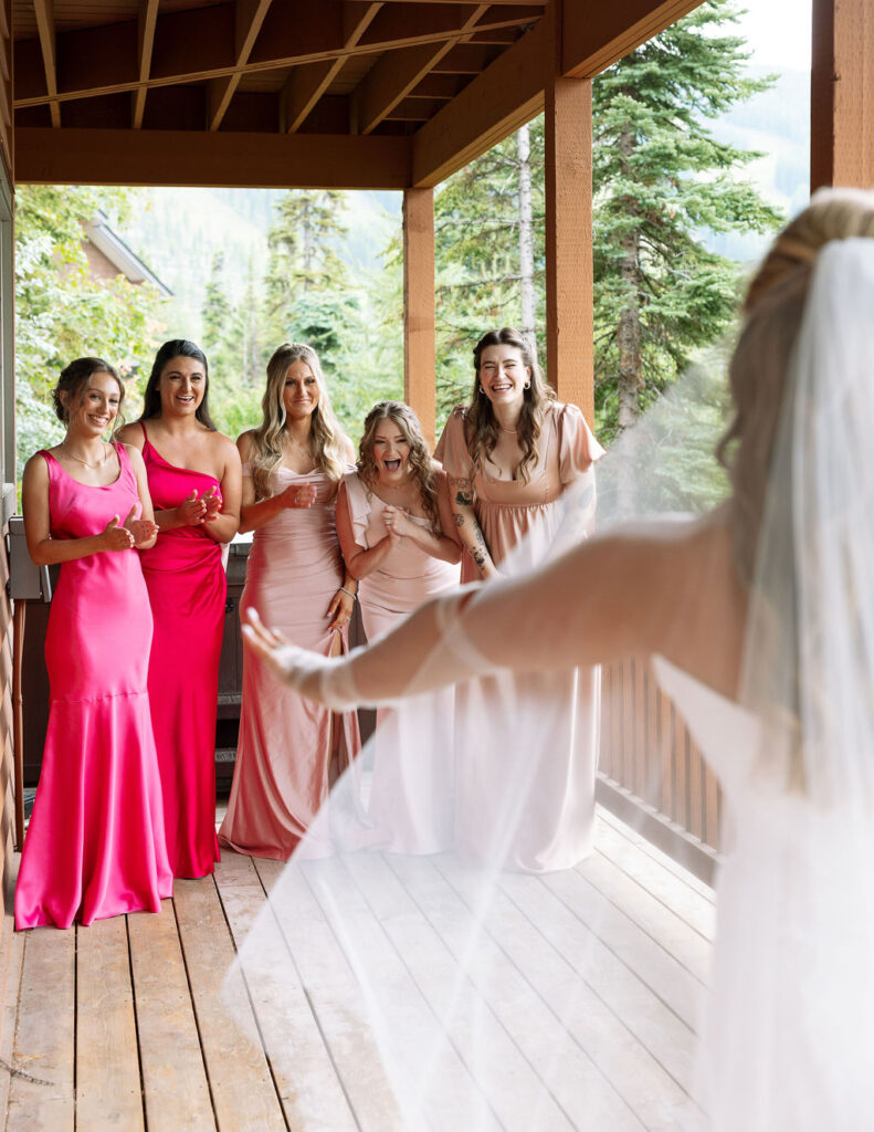 Bridesmaids in hot pink dresses pose with bride before Whitefish Montana wedding