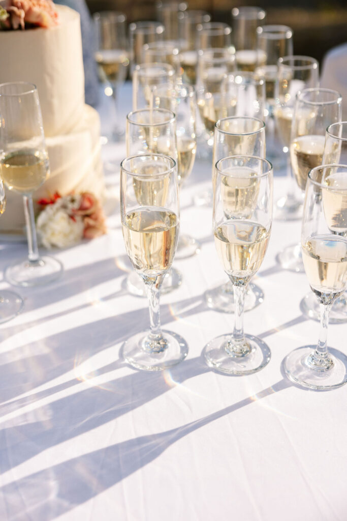 Close-up of champagne glasses and white wedding cake with soft floral accents at a Glacier National Park elopement.