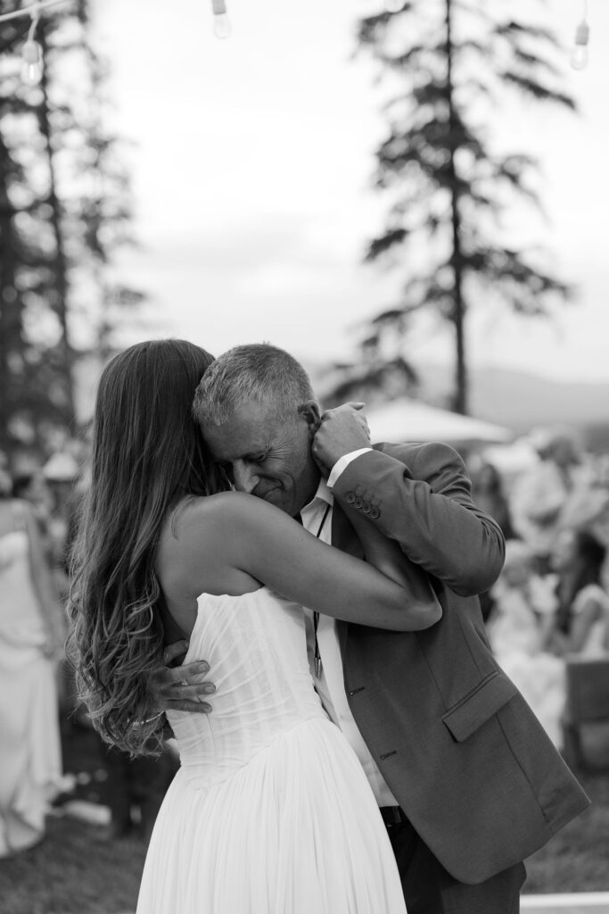 Bride and her father share an emotional father-daughter dance in black and white, capturing a quiet moment of connection at a Montana wedding celebration.