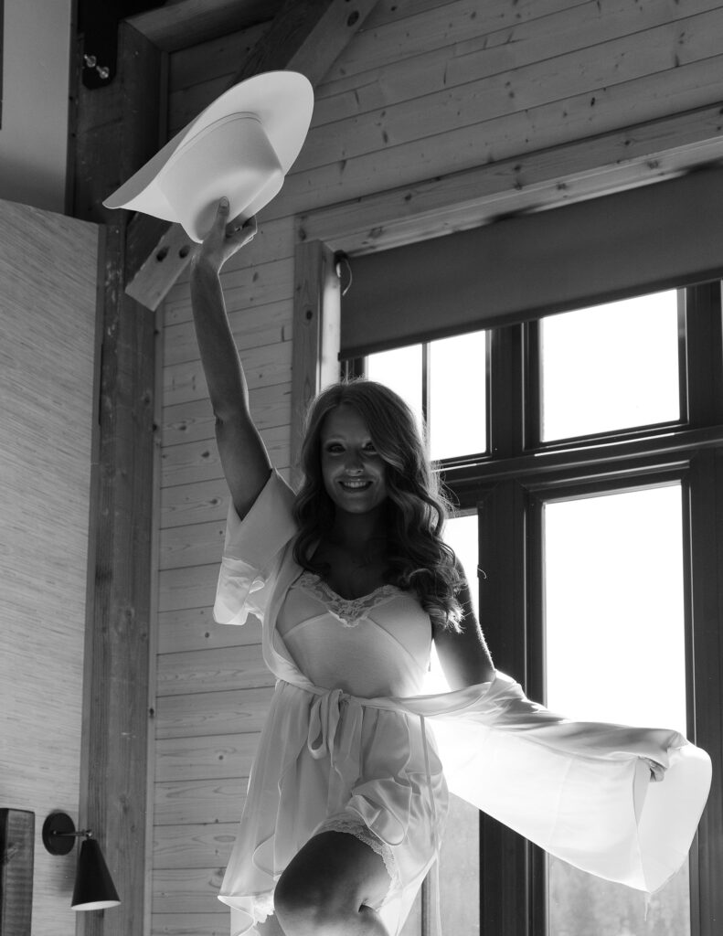 Clydesdale Outpost bridal details on a white bed, including a cowboy hat, lace gown, and gold accessories styled for a Montana elopement.