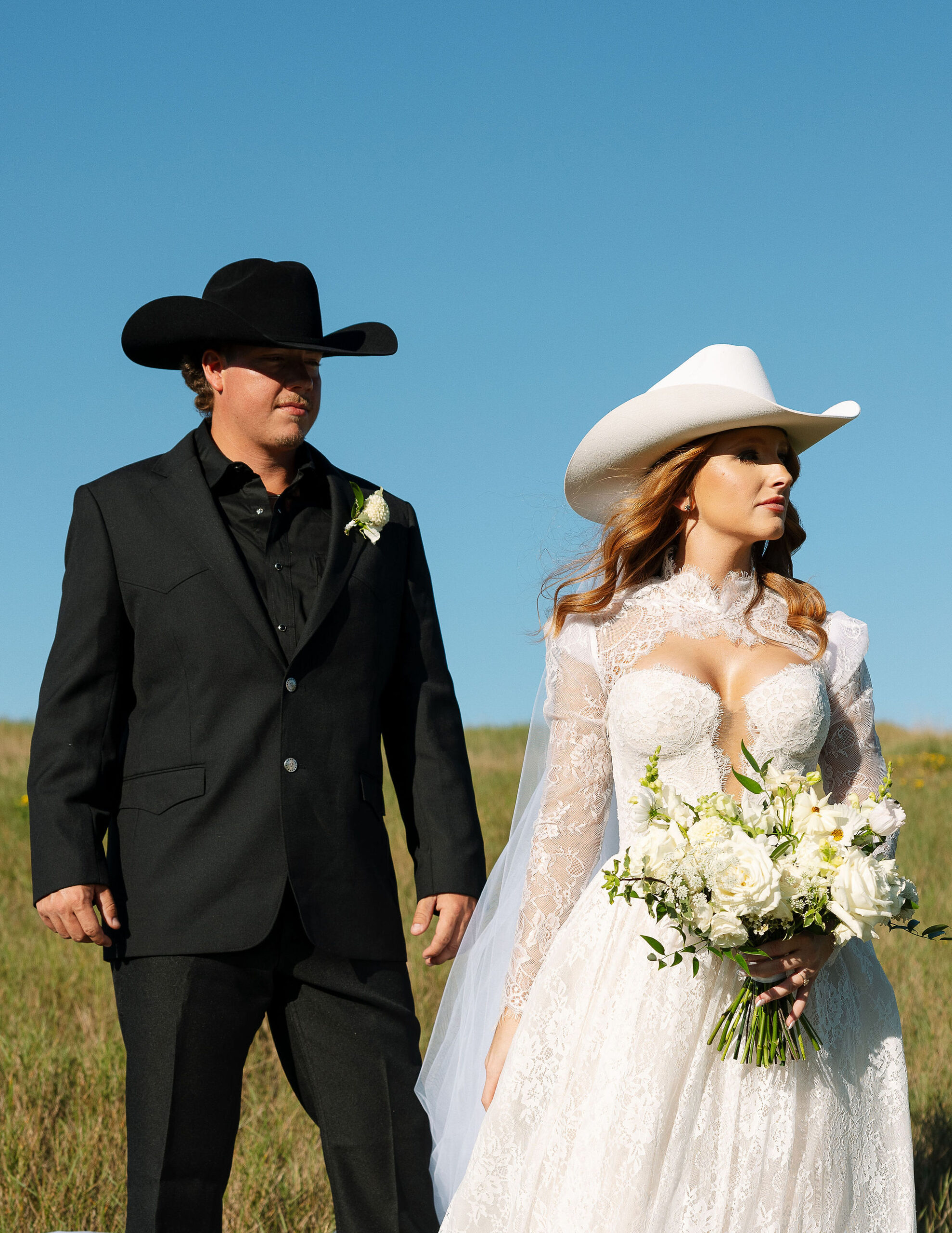 Bride and groom walking through a Montana field at Clydesdale Outpost, showcasing timeless Western wedding style.