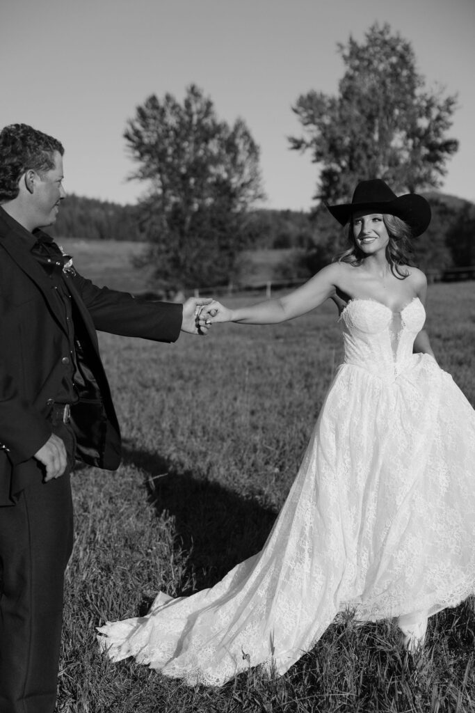 Bride resting on the groom’s arm as he carries her through the grass at Clydesdale Outpost, surrounded by wild Montana landscape.