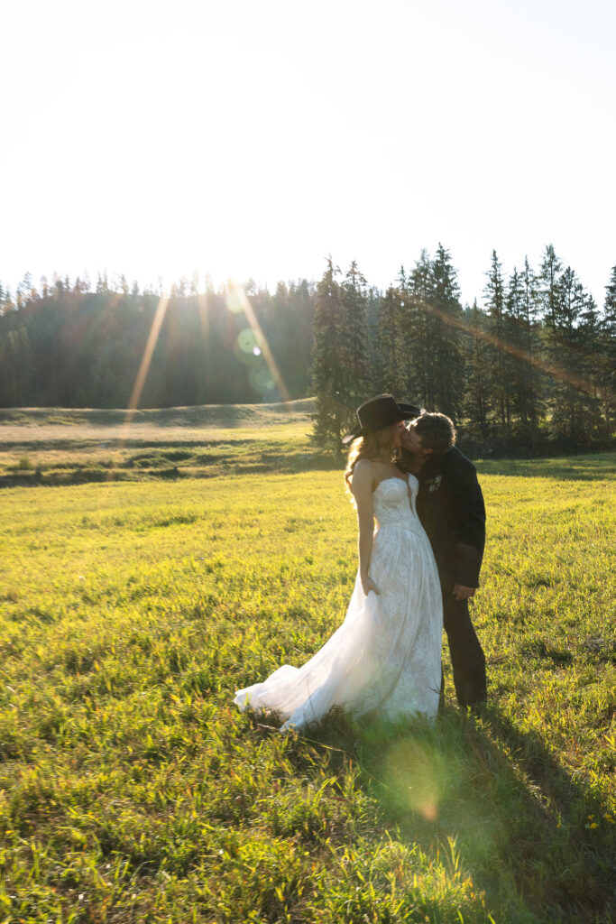 Bride and groom walking through open Montana fields with mountains behind them, celebrating their Western elopement at Clydesdale Outpost.