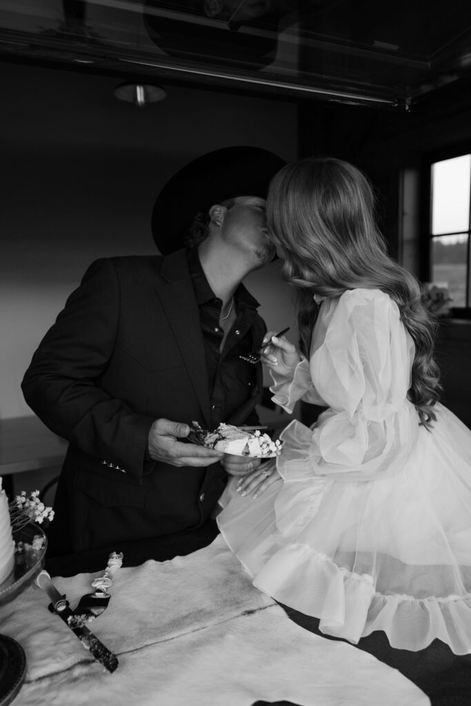 Bride and groom sharing a sweet moment cutting their wedding cake inside the cozy cabin at Clydesdale Outpost in Whitefish, Montana.