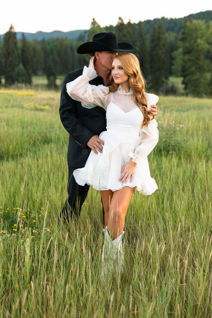 Bride walking hand in hand with her groom across a wild Montana meadow during their intimate Clydesdale Outpost elopement.