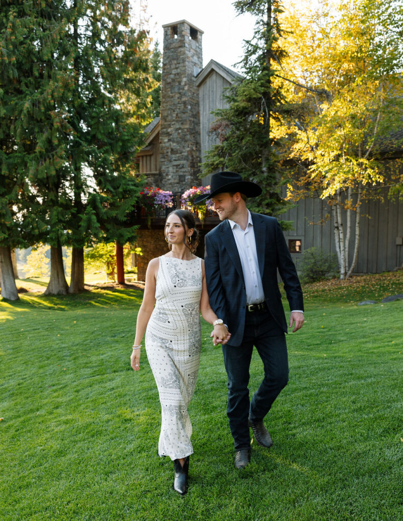 Bride and groom walking on the lawn in front of the lodge