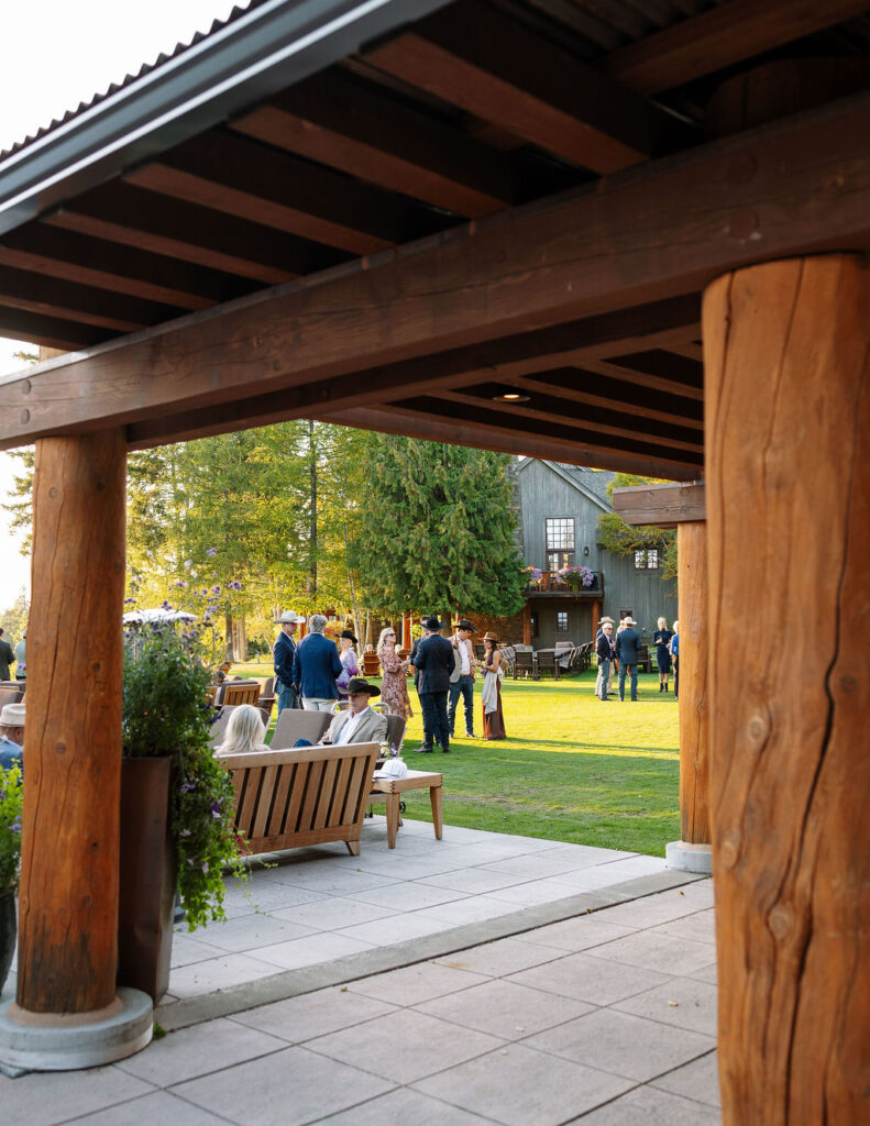 Guests walking and chatting beneath timber beams and stone columns at the Iron Horse clubhouse patio