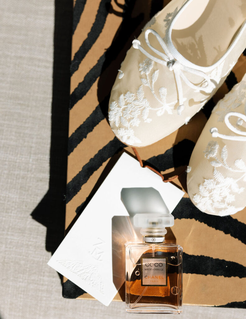 Close-up flatlay of bridal details with lace fabric and perfume bottle