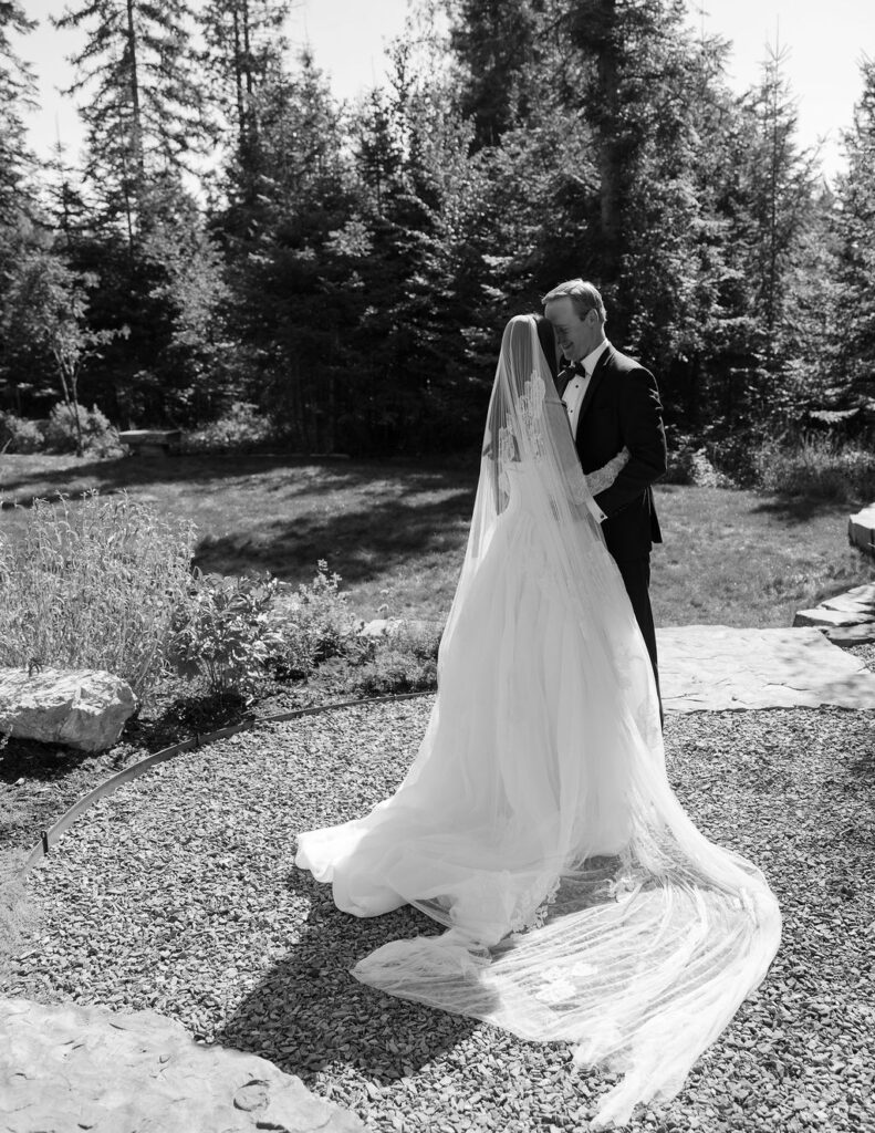 black and white photo of the bride and groom walking together on a garden path