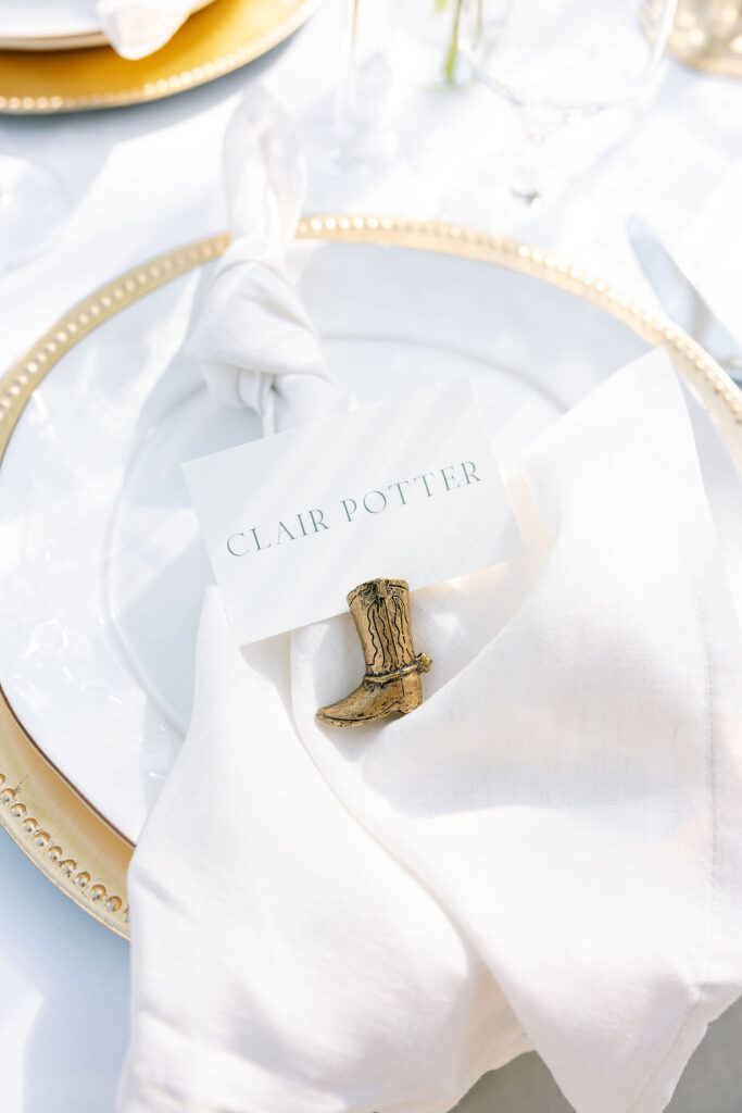 Wedding place setting with white napkin and name card on gold-rimmed plate
